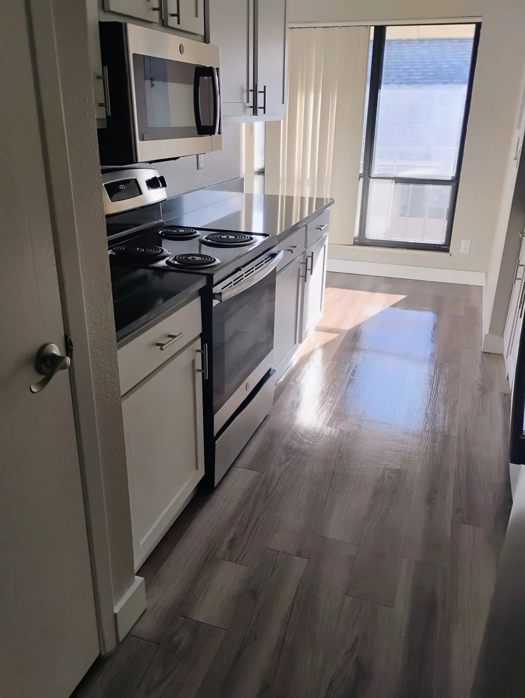 Galley kitchen with gleaming floors and clean stainless appliances